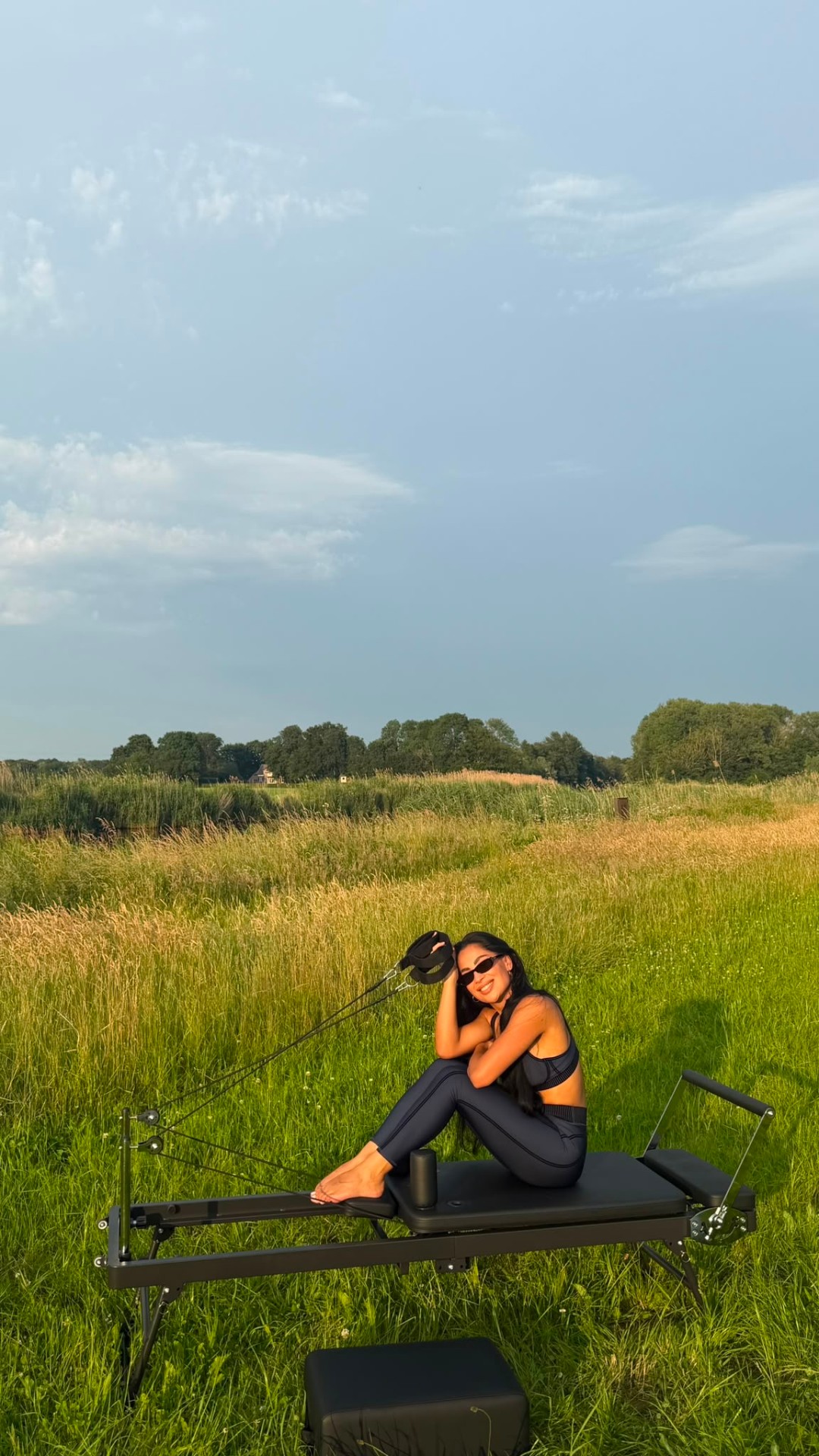 Lachend buiten — reformer pilates in een grasveld bij zonsondergang