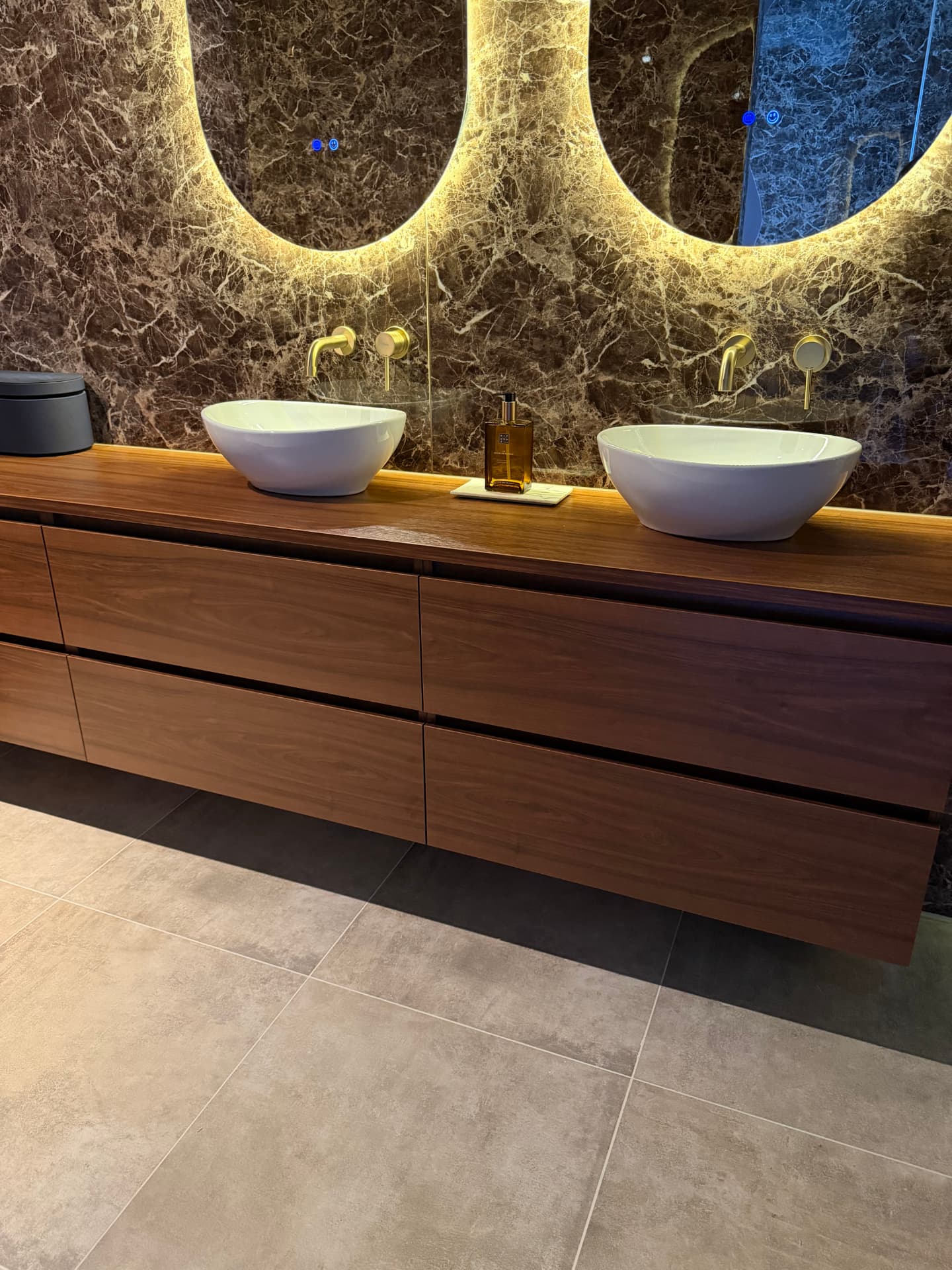 Luxe make-up ruimte met marmer, houten meubel en verlichte spiegels
